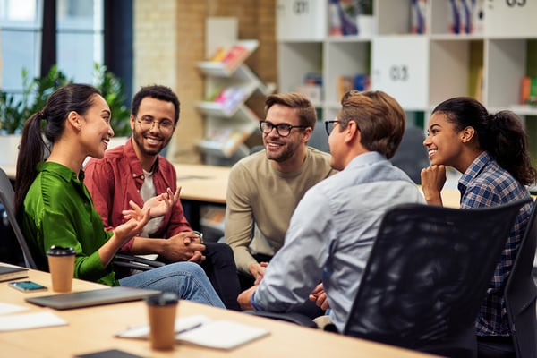 smiling-co-workers-sitting-together-in-office-talking